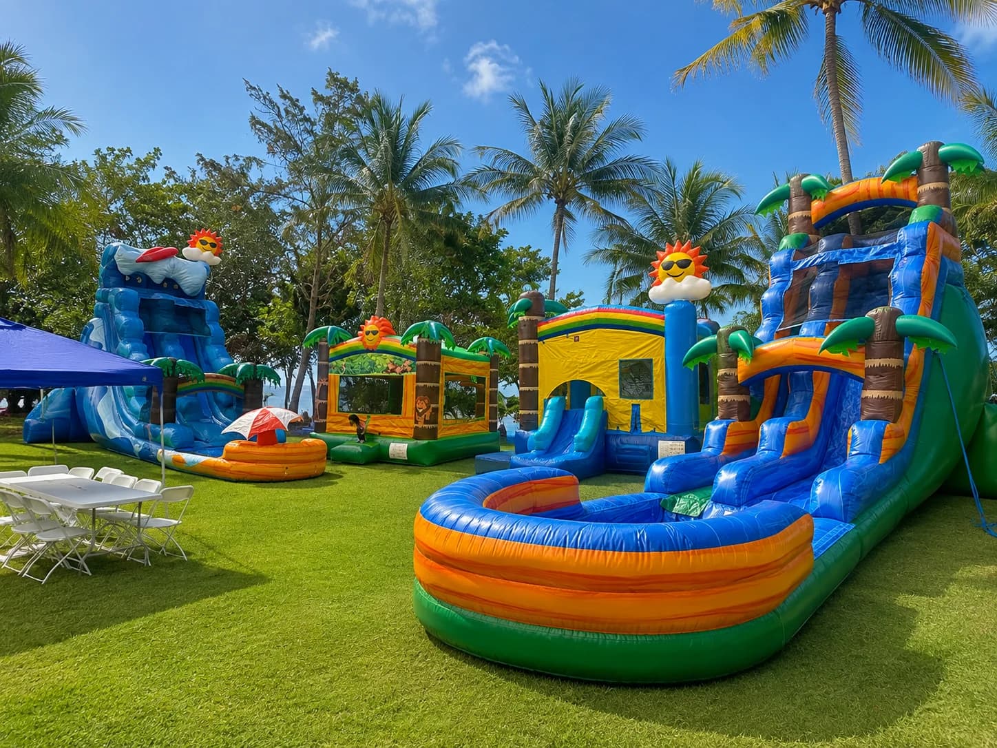 Guam Cherry Rentals complete party setup with four inflatables, tables, chairs and blue canopy